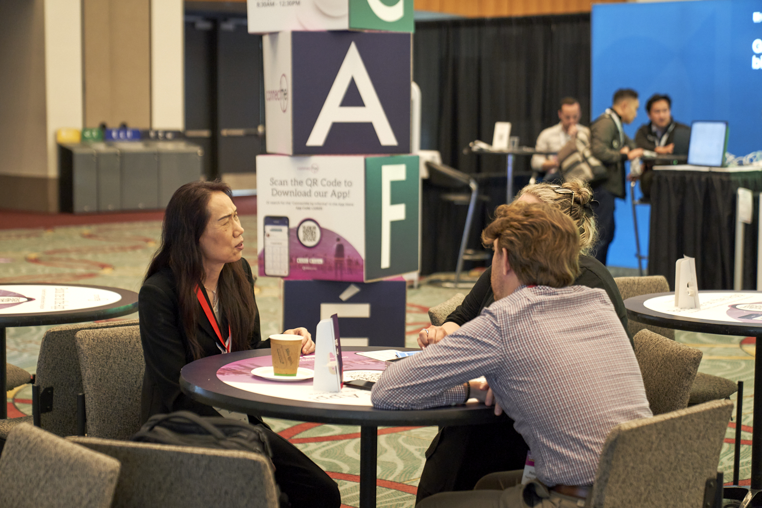 Bioprocessing attendees at BPI West in discussion at a table in the exhibition hall.