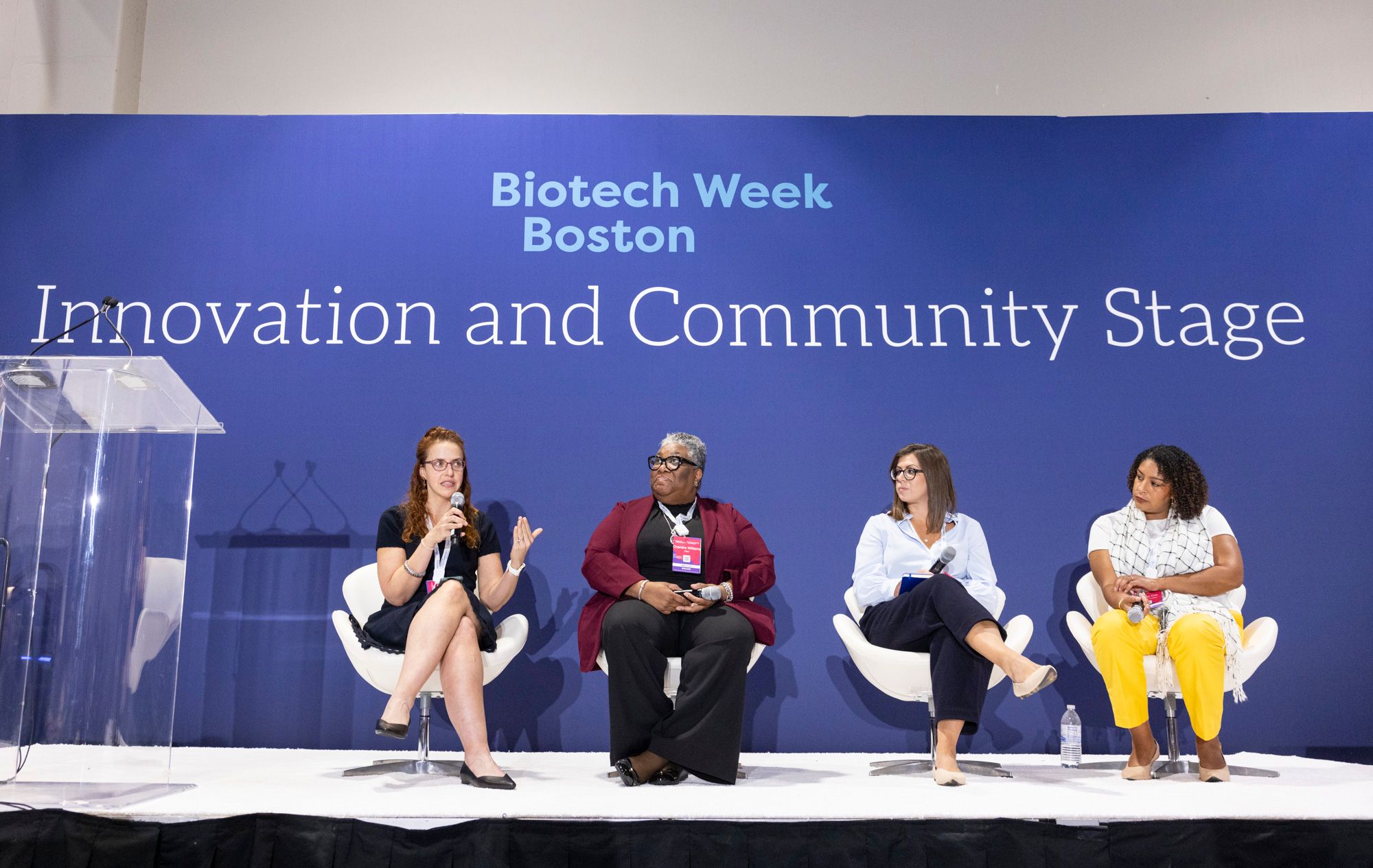 A panel of four female speakers sit on the Innovation and Community Stage at Biotech Week Boston.
