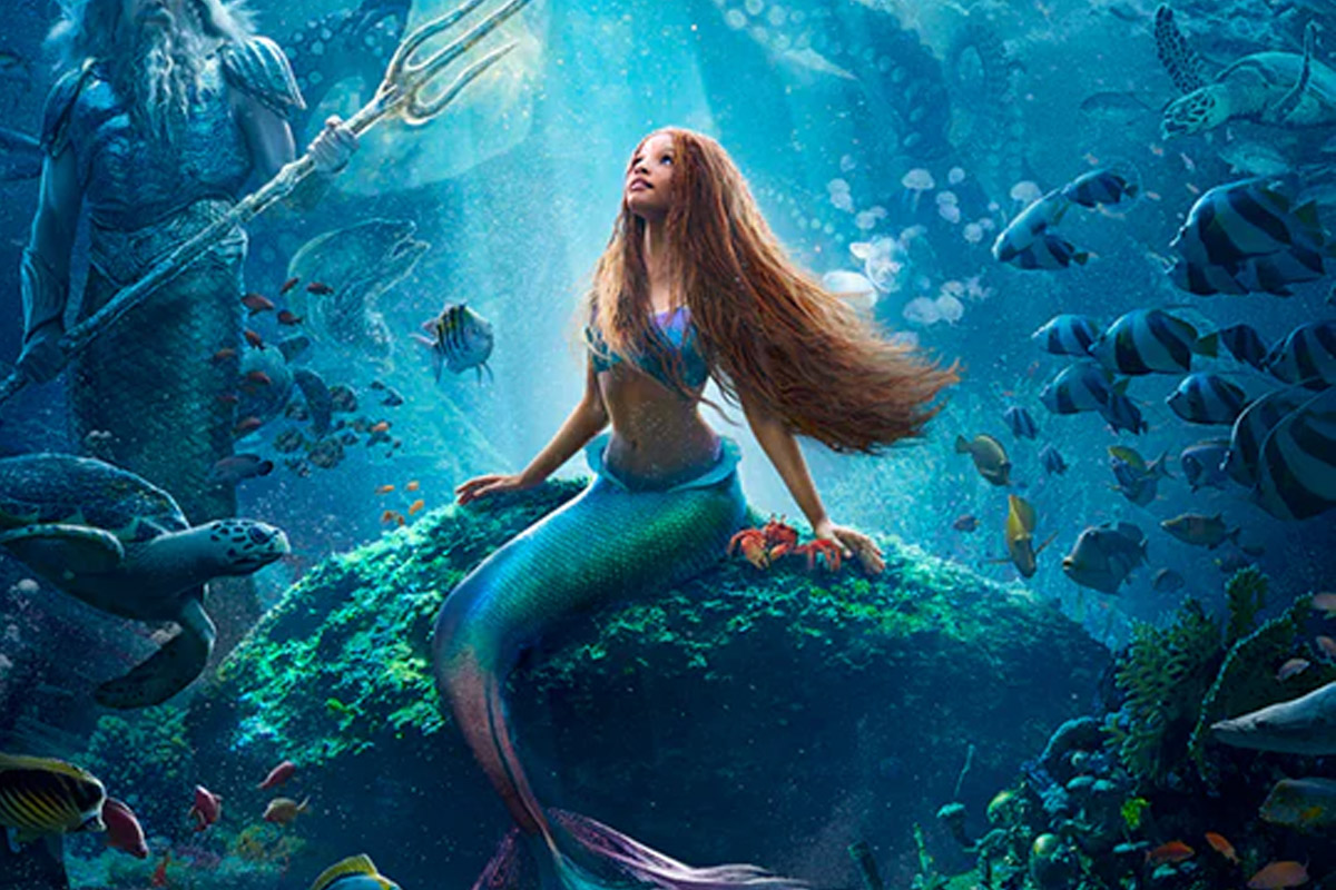 Ariel from the 2023 The Little Mermaid sits on a rock underwater