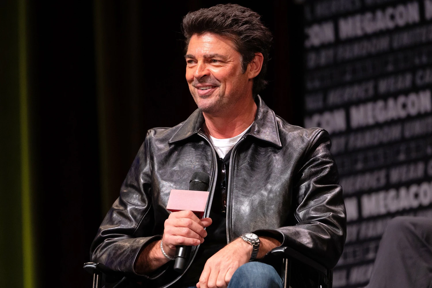 Karl Urban speaking on stage during a celebrity panel at FAN EXPO Dallas.