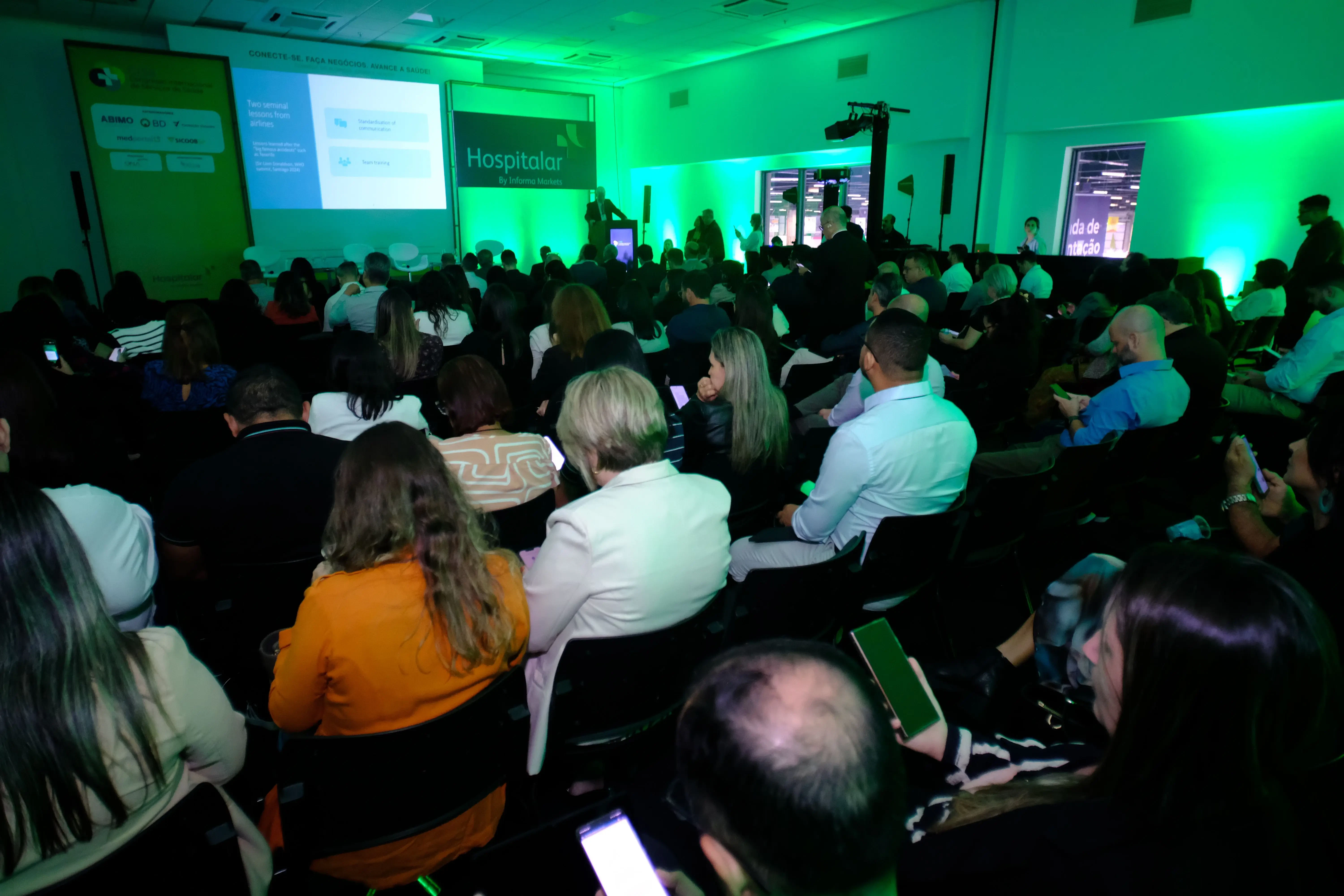 Auditório lotado na Hospitalar 2025 assistindo palestra sobre lições da aviação para a segurança do paciente.