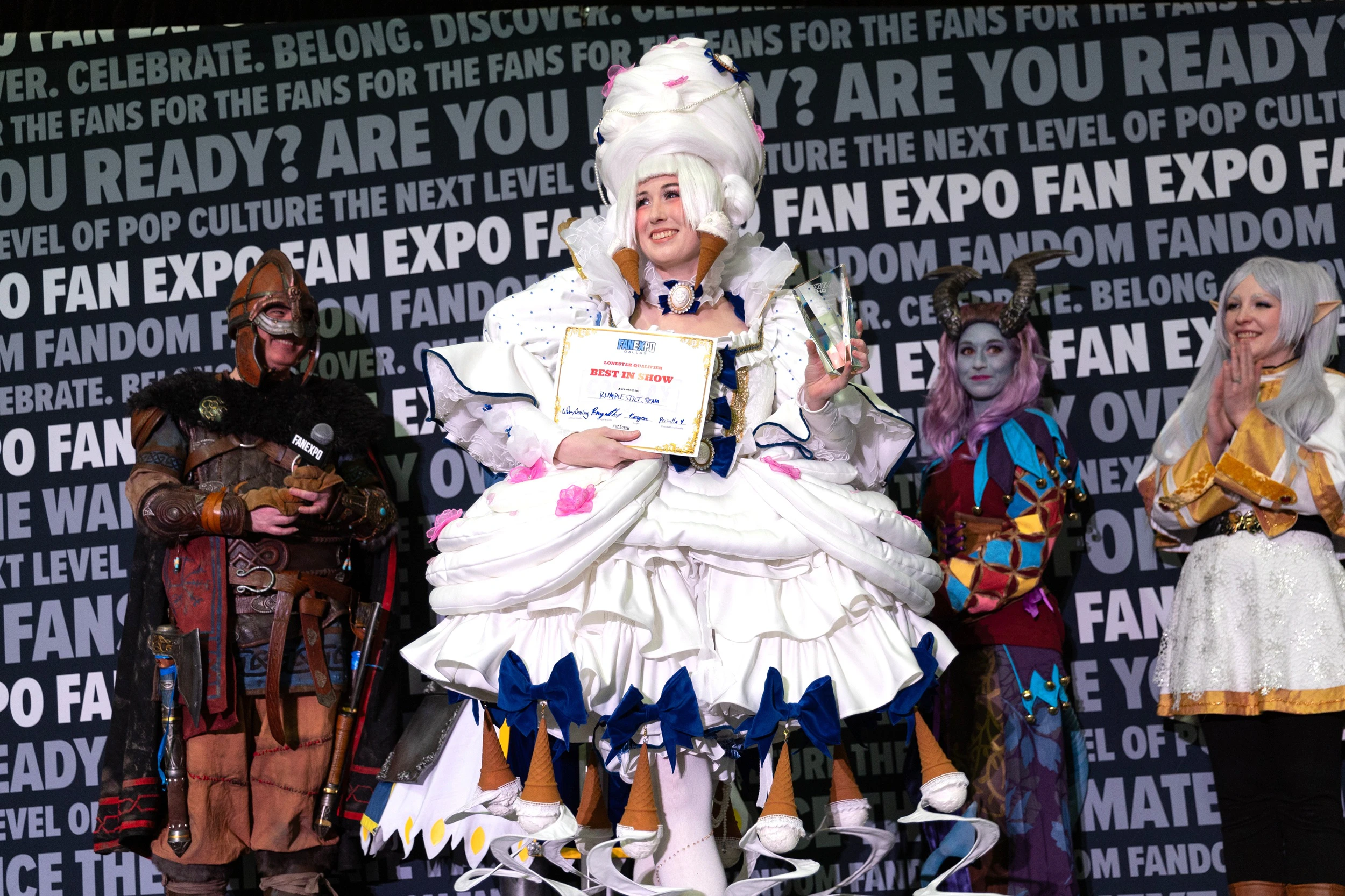 Winner of the FAN EXPO Dallas Masters of Cosplay competition posing on stage with judges and fellow contestants.