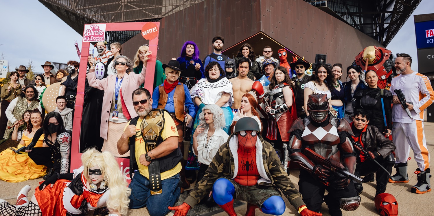 A large group of cosplayers poses outdoors, showcasing a diverse range of fandoms, from Spider-Man to various anime and superhero characters, at a Dallas FAN FESTIVAL meetup event.
