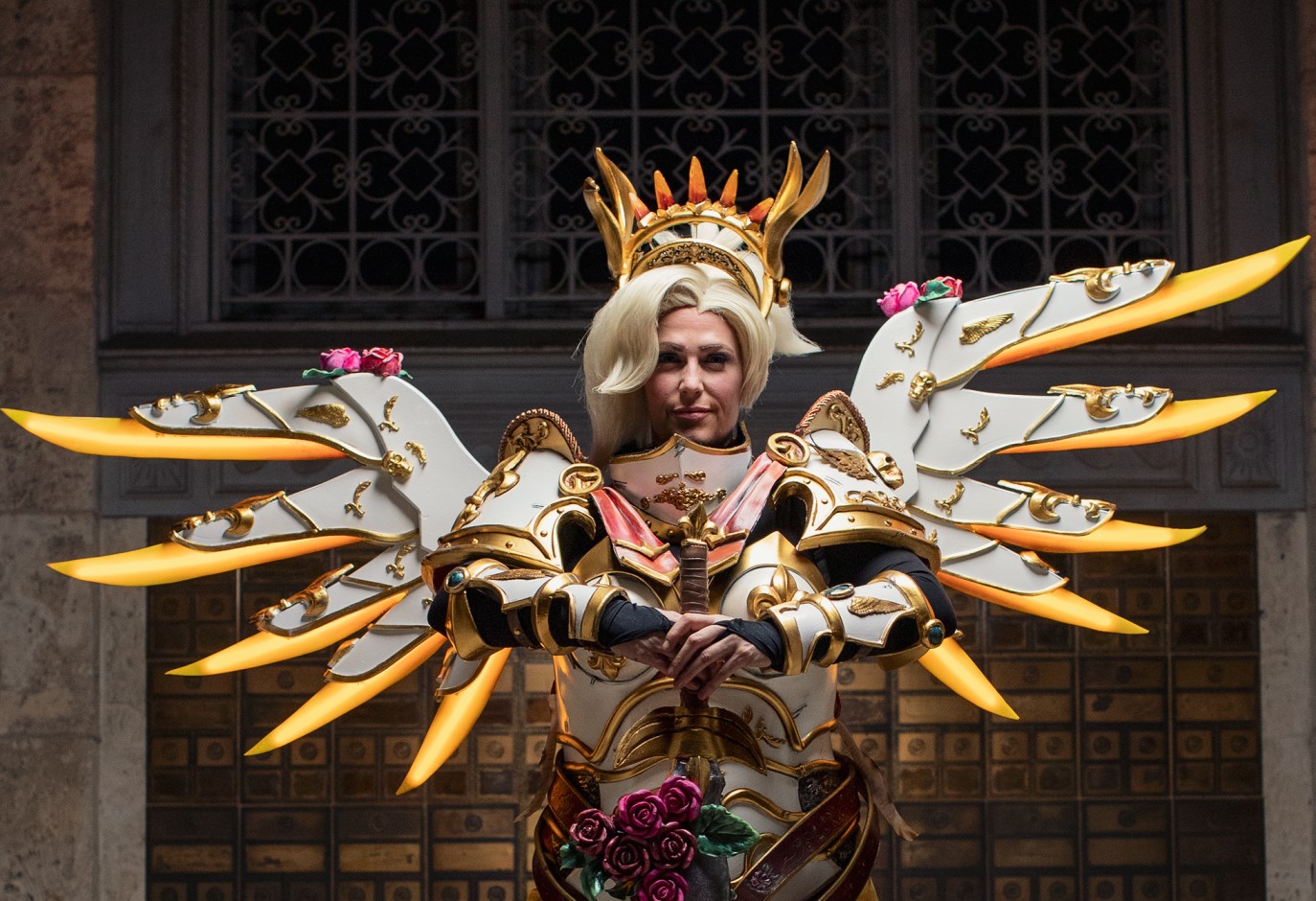 AVERA COSPLAY IN COSPLAY WITH LARGE WHITE WINGS WITH GOLDEN TIPS AND A BLONDE WIG