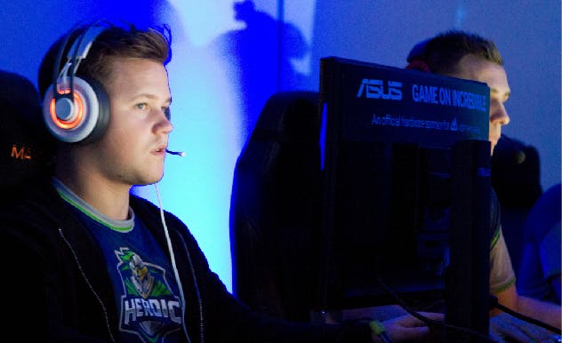 Fan in a gaming tournament wearing headphones and looking at a computer screen