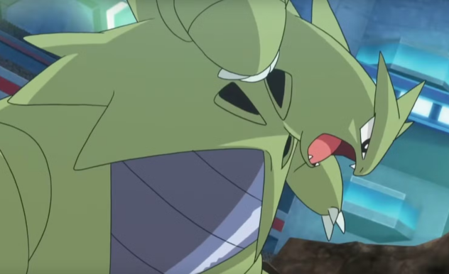 In battle, Tyranitar stands tall and menacingly, mouth open, with one hand outstretched and the other in a fist.