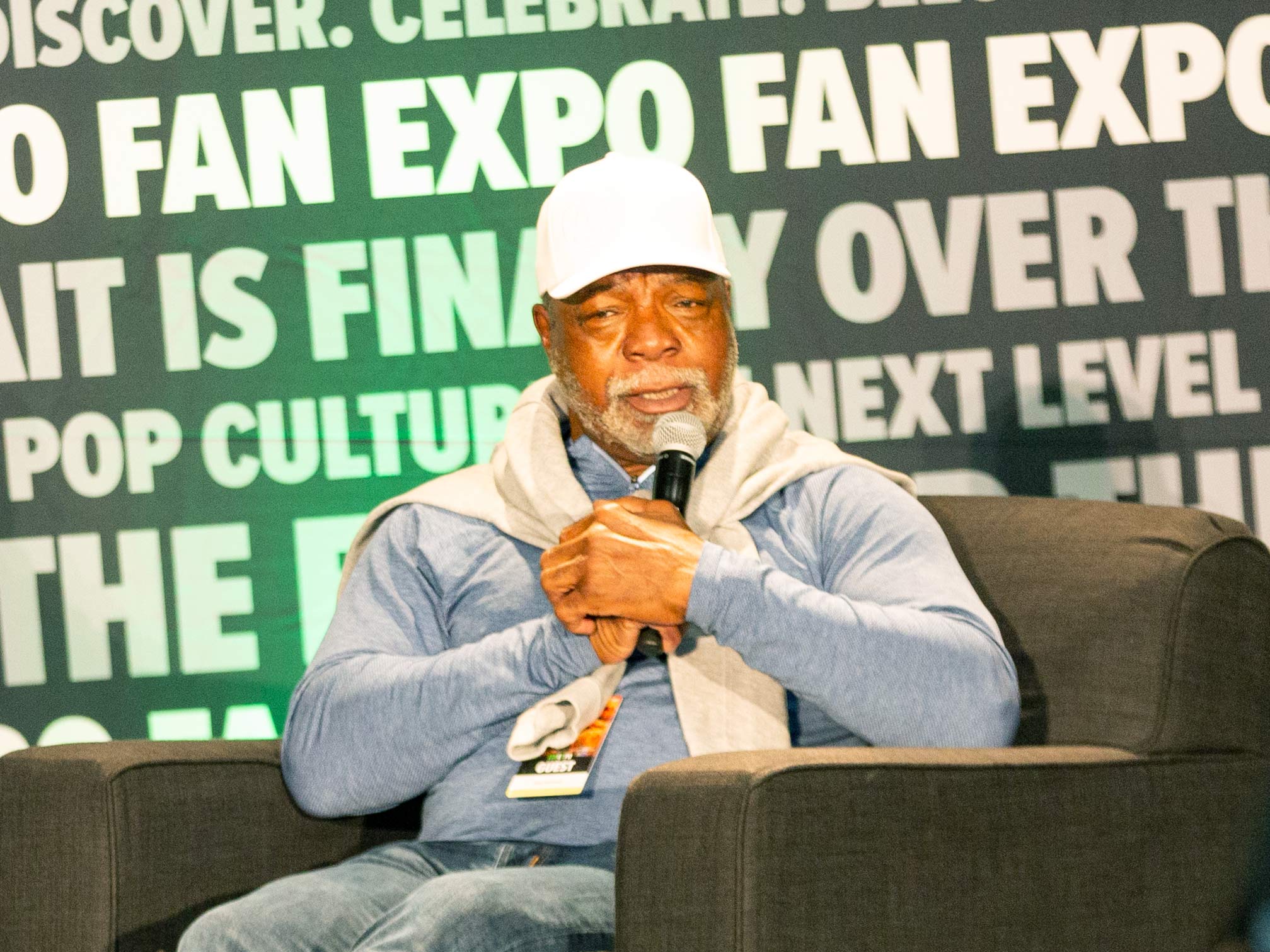 Carl Weathers on stage holding a microphone