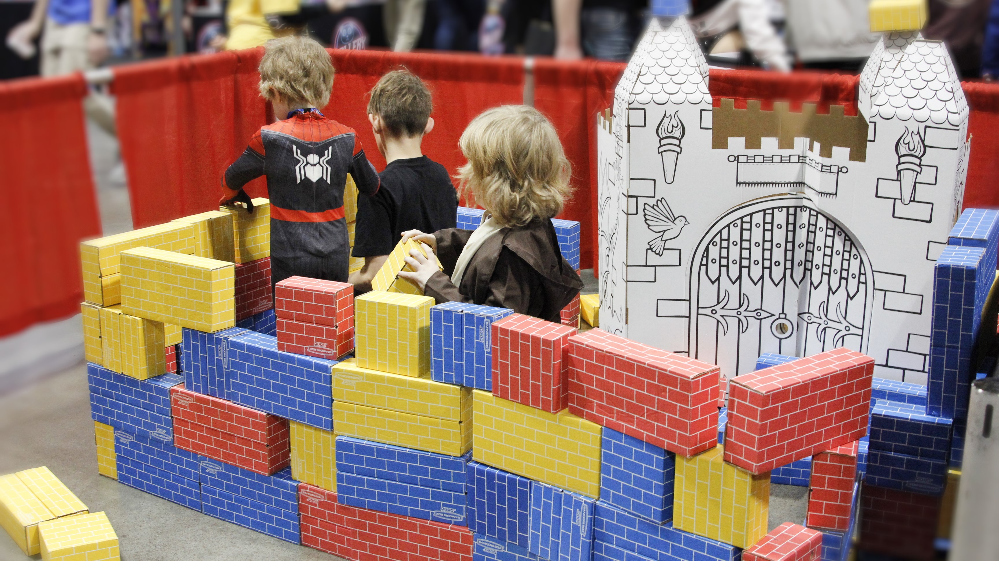 Three children play with toy bricks in the family zone