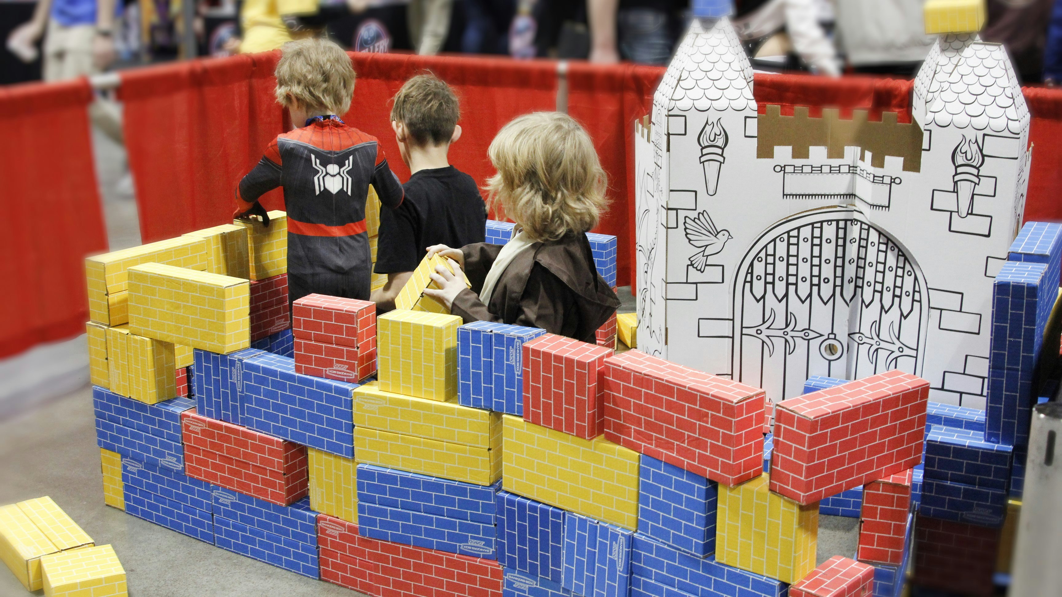 Three children play with toy bricks in the family zone