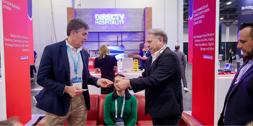 A photo of a man handing another man a business card at a trade show booth at Channel Partners conference and expo.