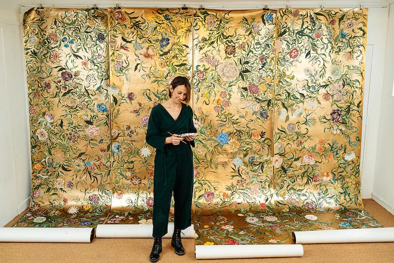 young white woman standing in front of golden wallpaper display