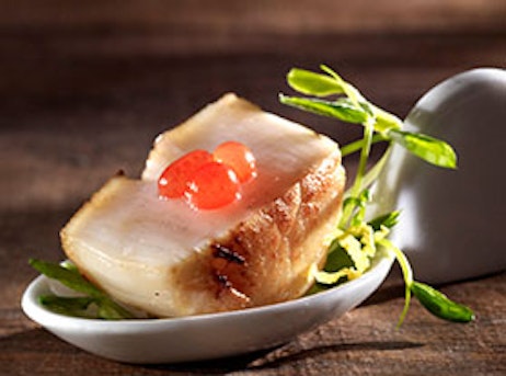 half of a scallop in a tasting spoon