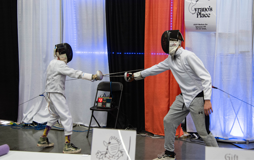 two people fencing behind the Cyrano's Place booth in the community zone