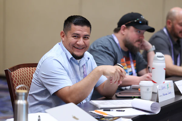 Attendee smiling while participating in an educational session at HDI Service & Support World, exploring conference topics that match his professional goals.