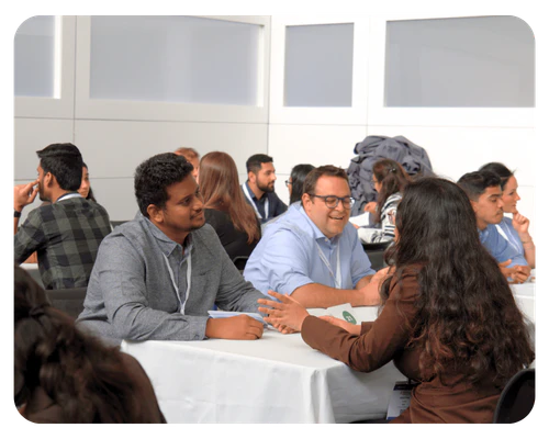 Several individuals seated at tables, actively networking and sharing ideas in a professional environment.