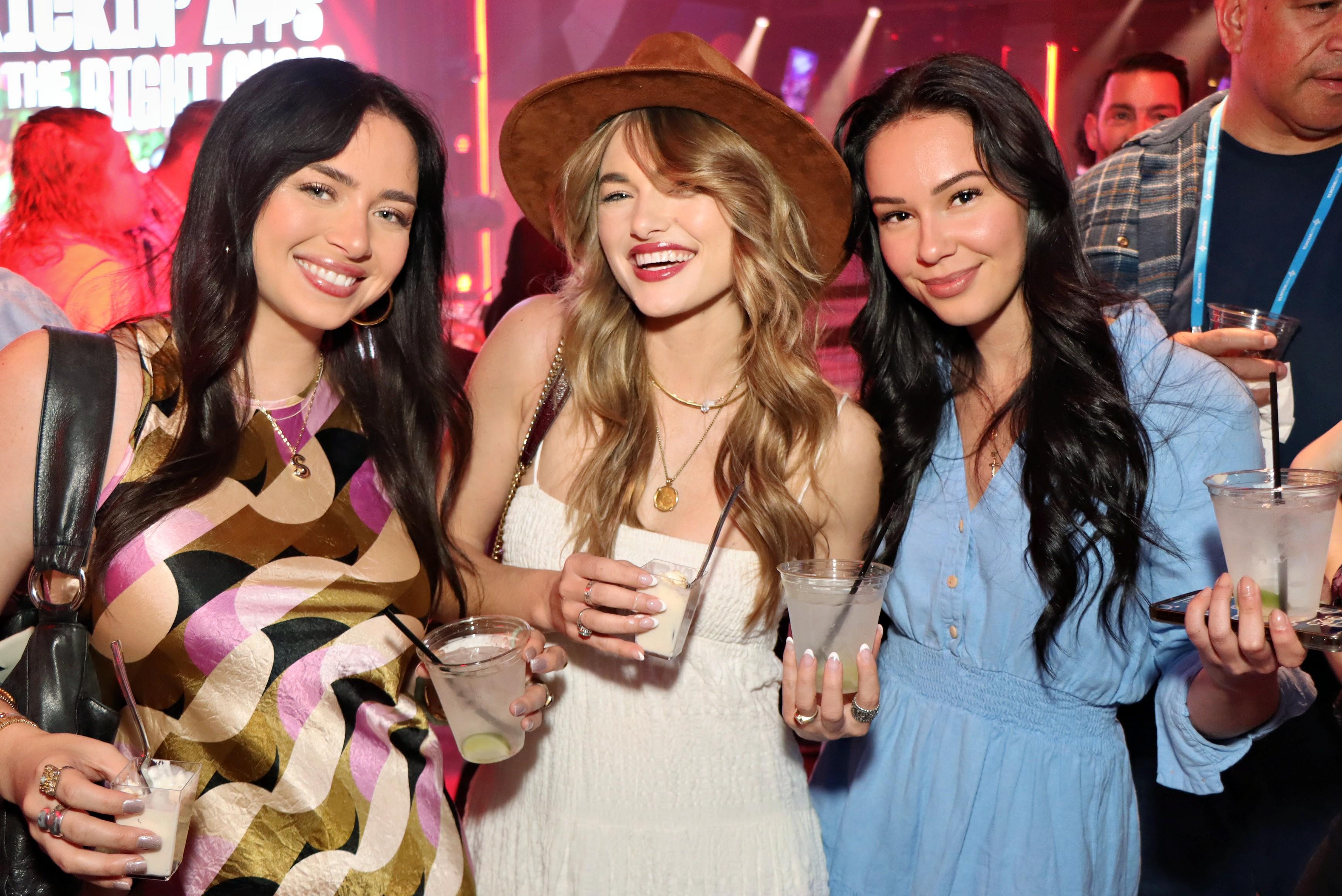 Group of three women smiling and holding drinks at a networking party