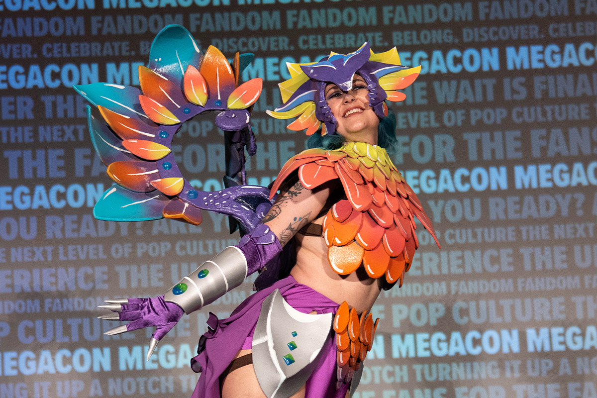 A Cosplayer wearing a purple, orange, and blue scaled outfit