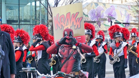 A deadpool cosplayer holds up heart hands during the POW parade