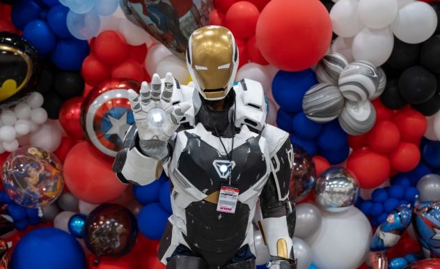 An Iron Man cosplayers in a black & white Iron man suit poses with their hand raised