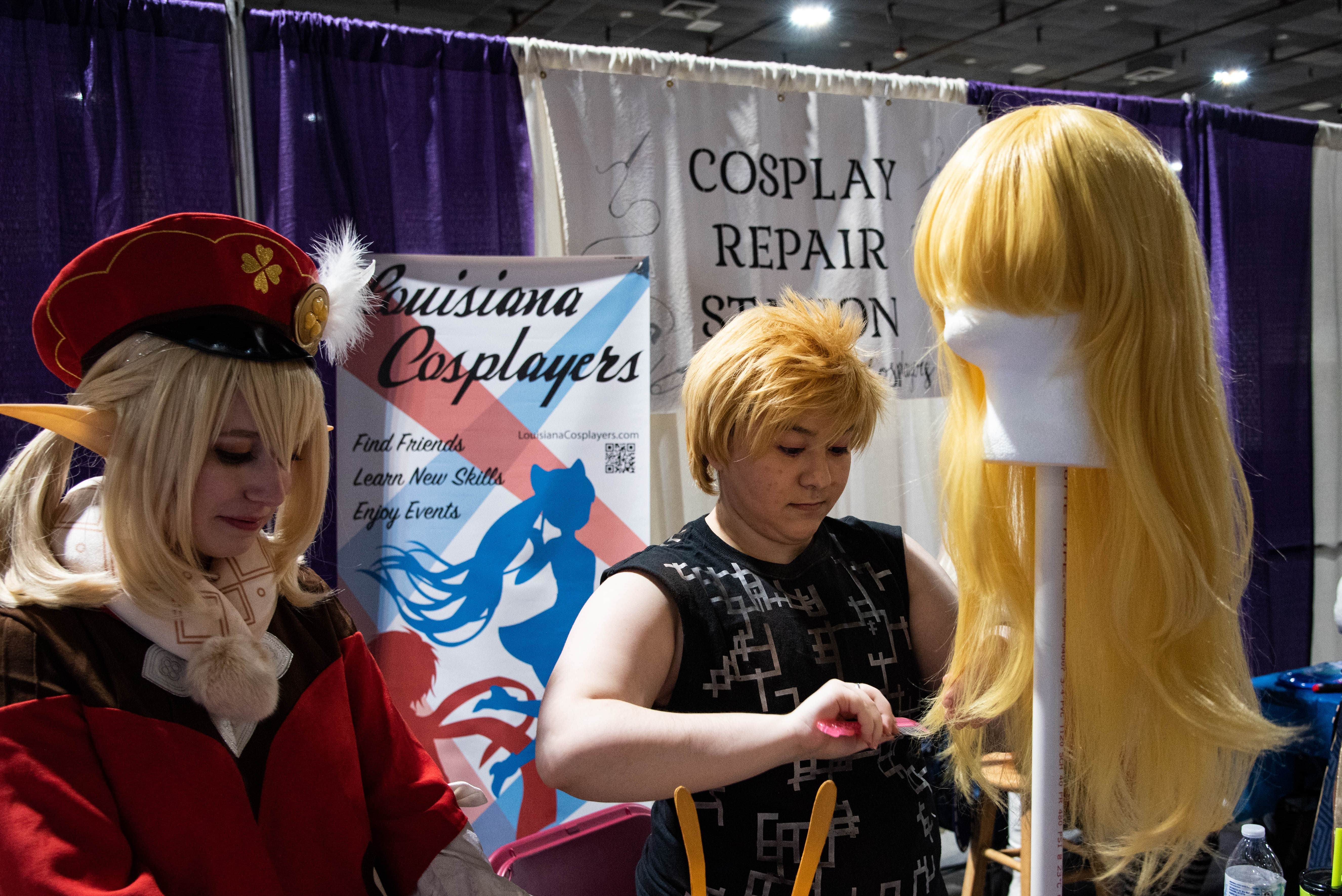 Several cosplayers at the Louisiana Cosplayers community booth, prepping cosplays.