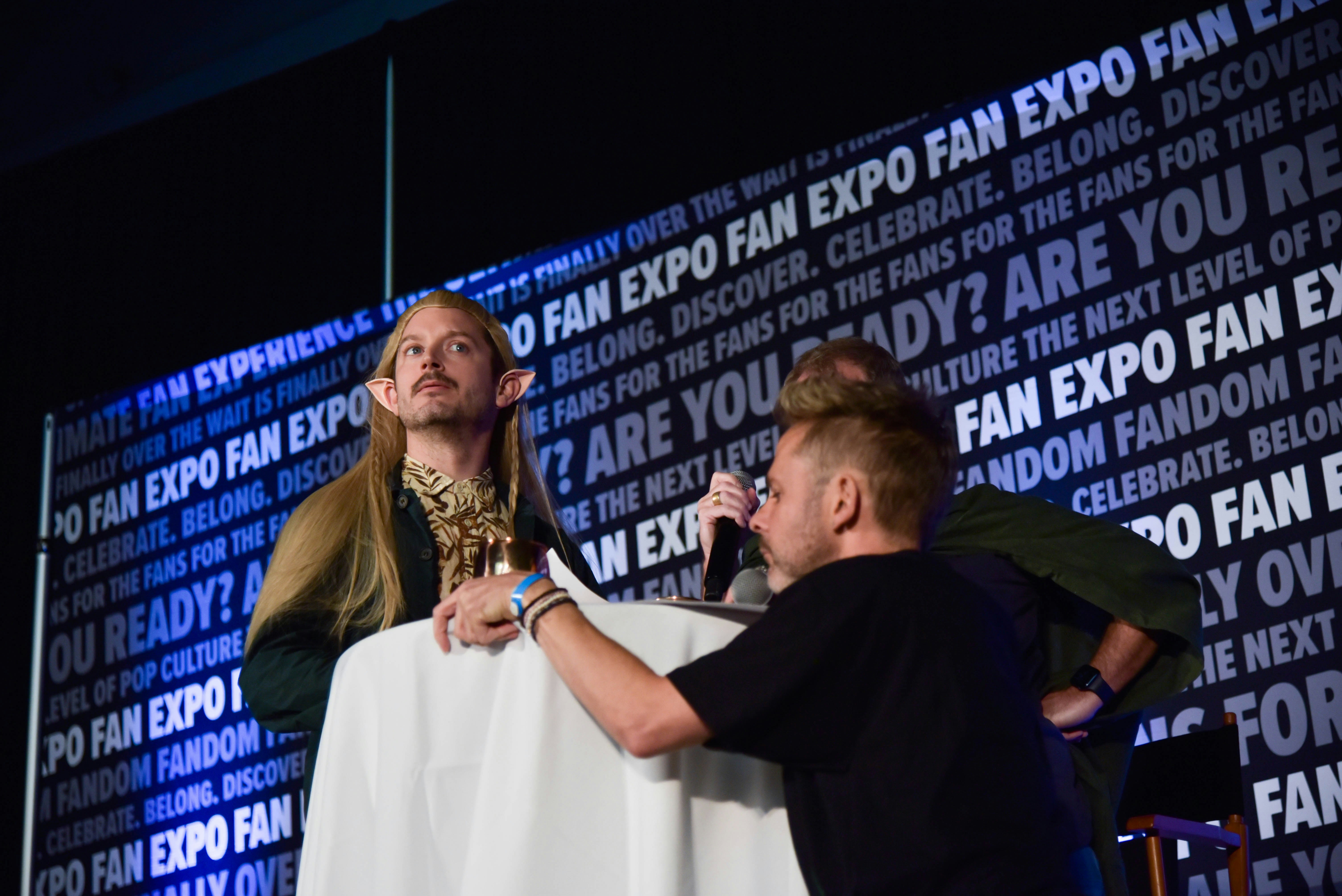 Elijah Wood (acting as Legolas) with Dominic Monaghan (acting as Gollum) across him at their special event.