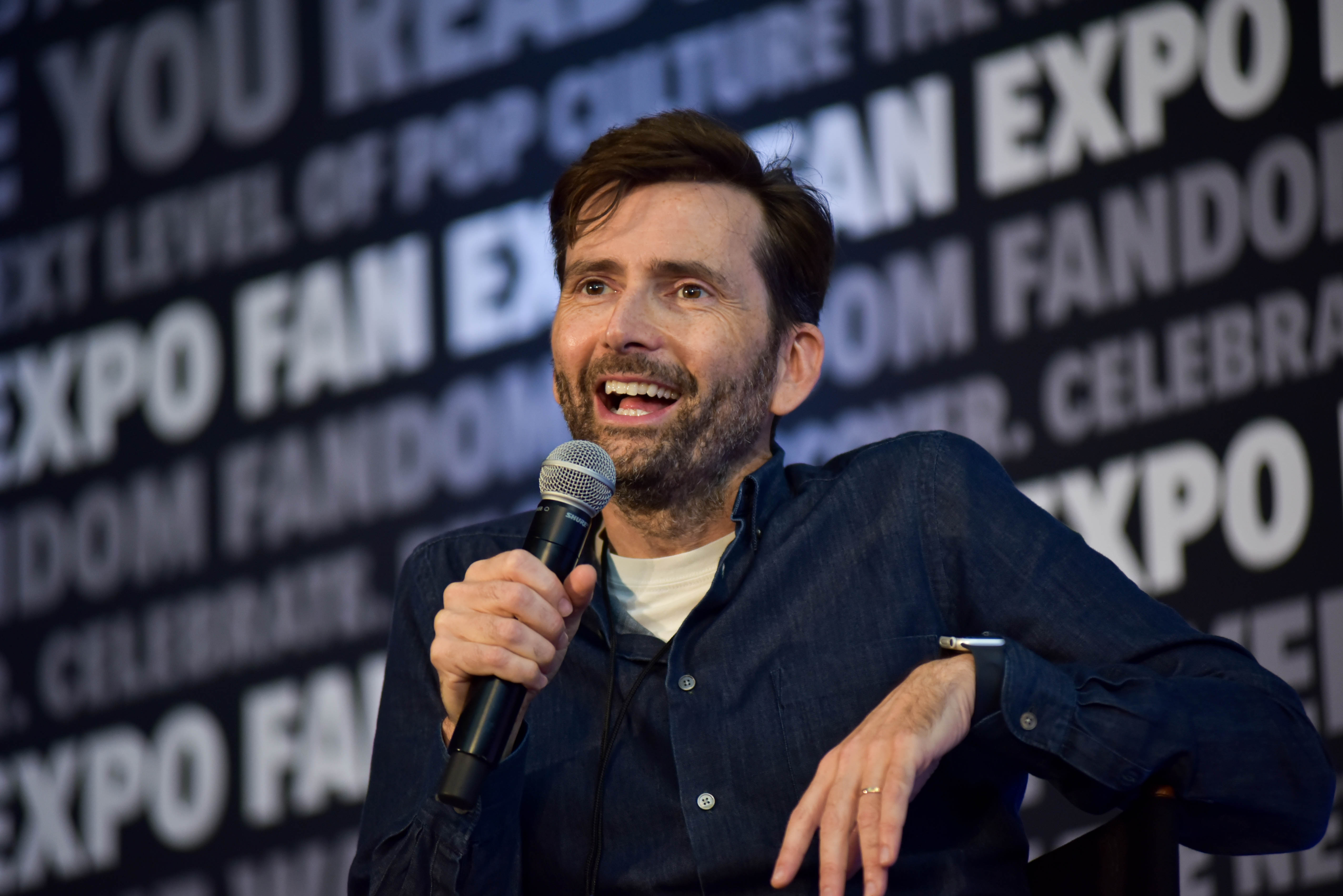 David Tennant giving a candid answer into the microphone in his hand during his panel.