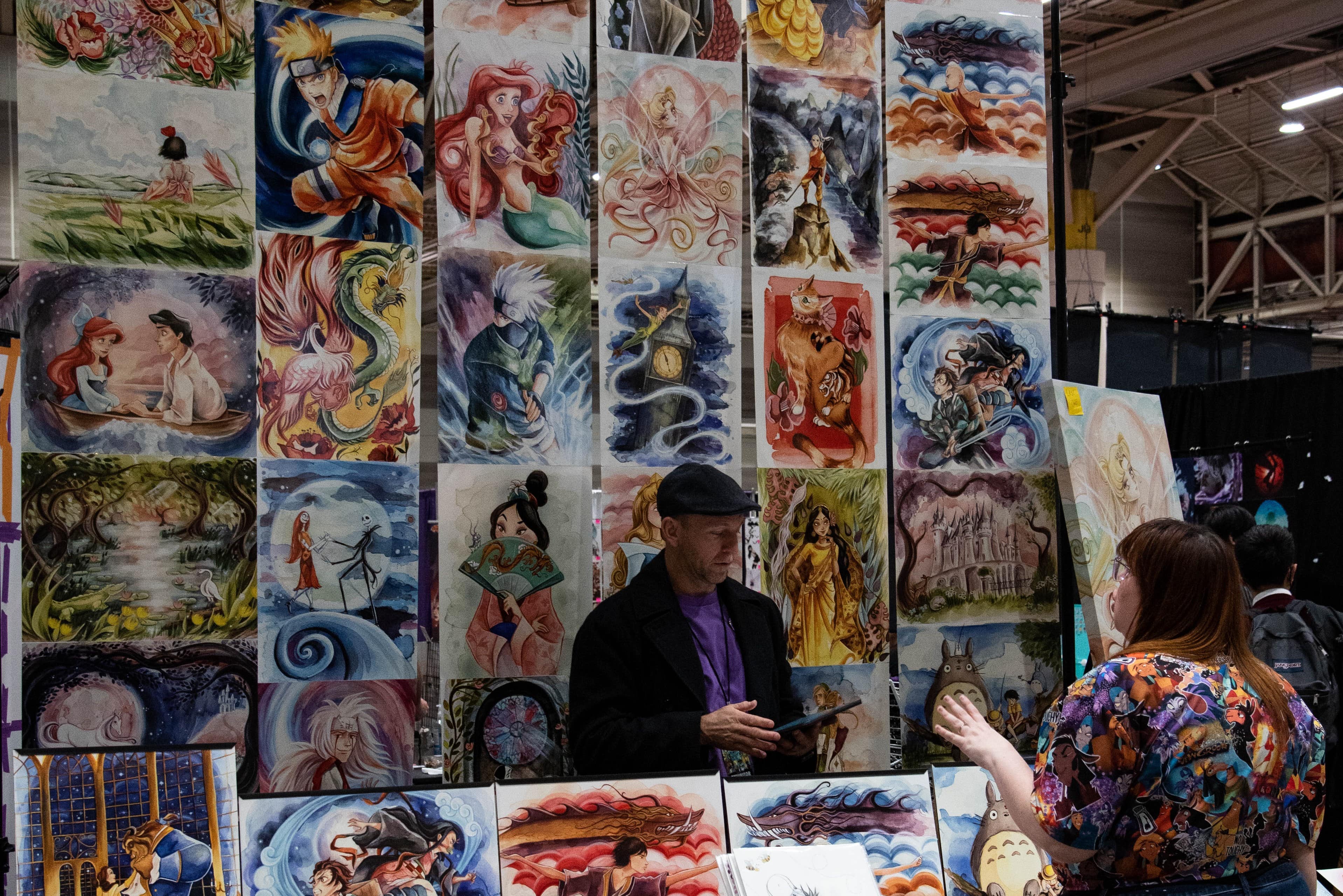 A con-goer shopping for posters at an artist alley booth.