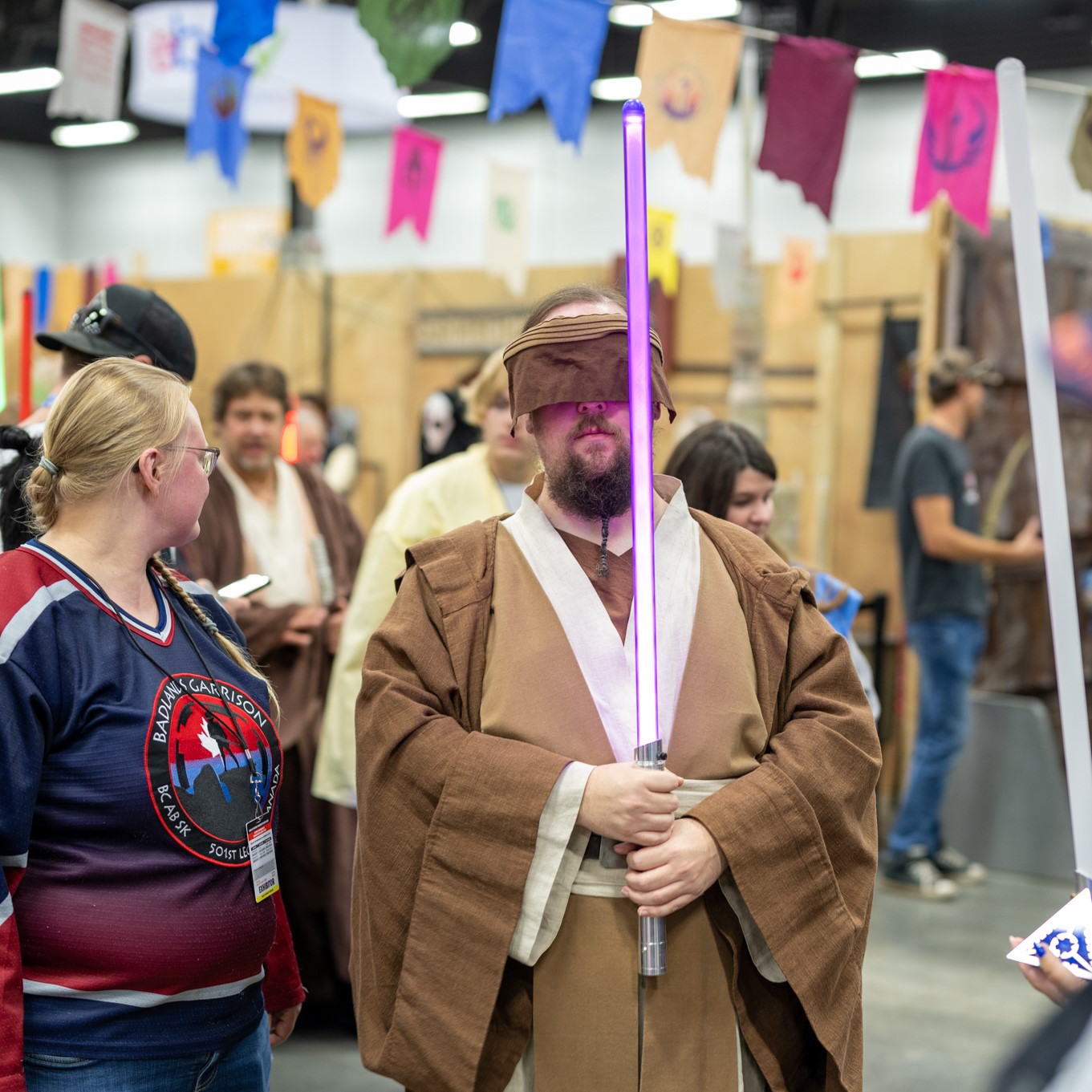 A cosplayer dressed as Obi-Wan holding a lightsaber