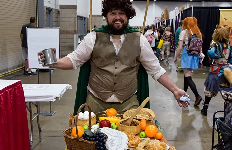 man cosplaying as a hobbit eating second breakfast, with a table full of food in front of him