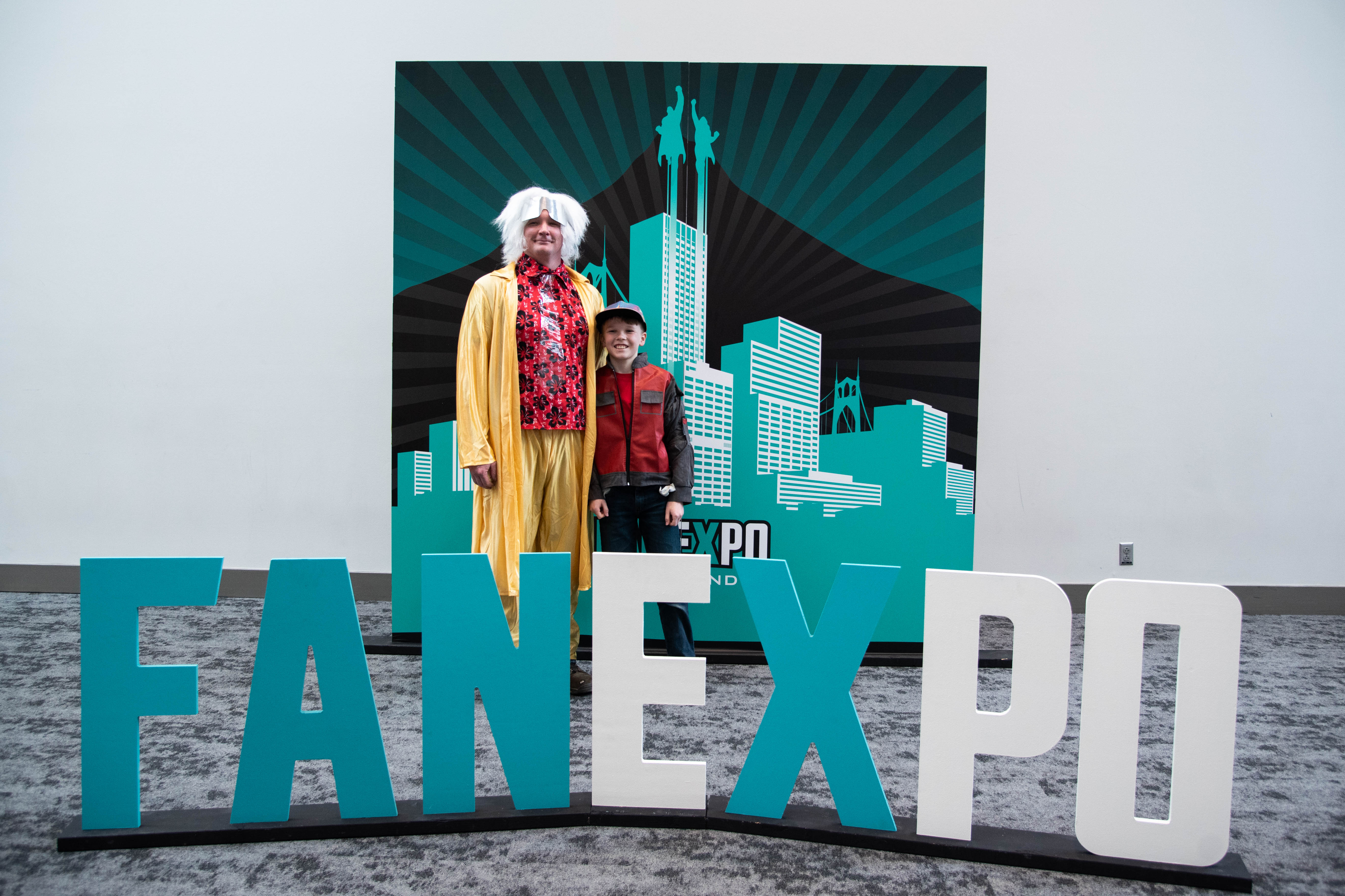 a father and son duo dressed as Doctor Emmett Lloyd and Marty McFly pose with our FAN EXPO Portland photo op