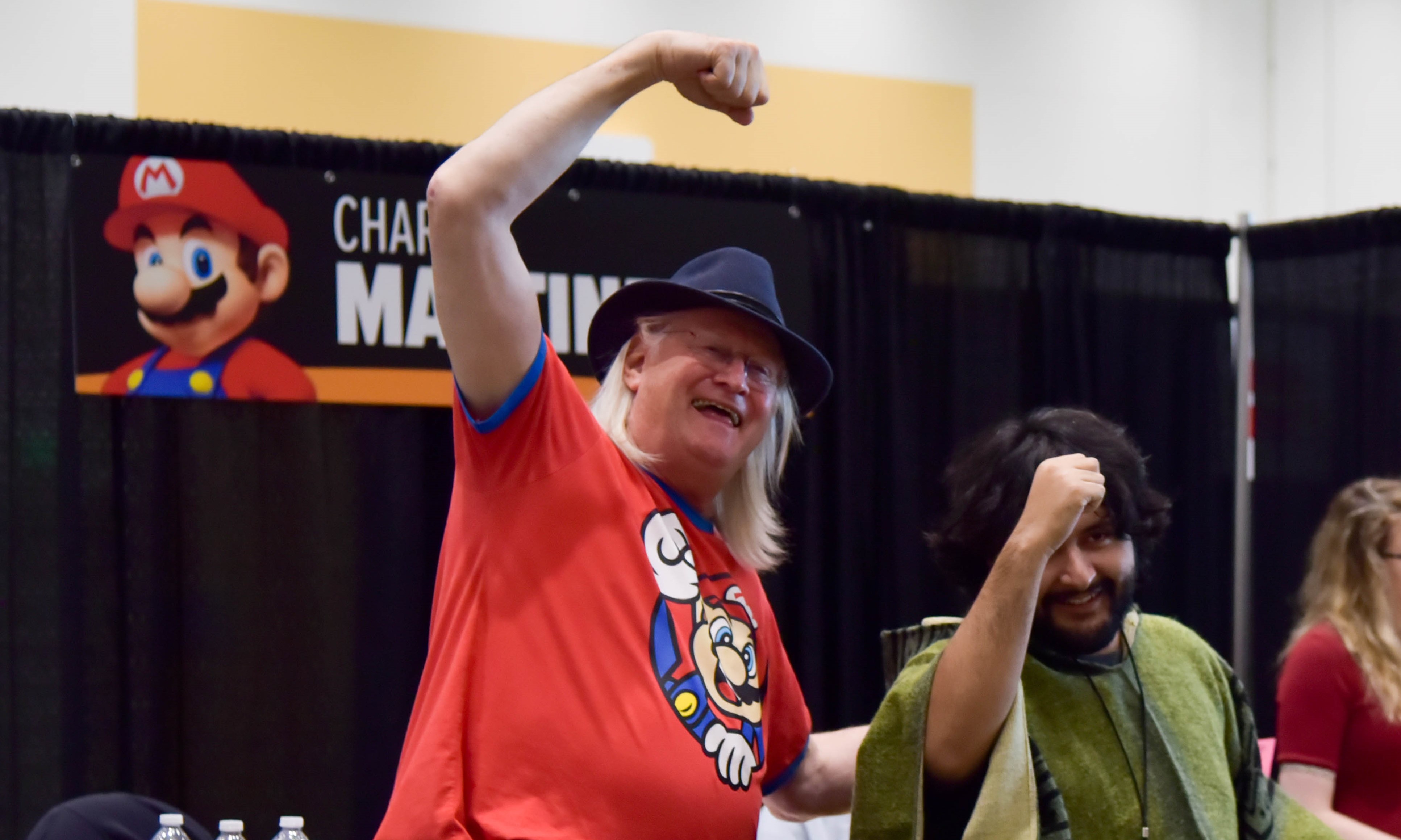 Charles Martinet at his booth with a fan doing the Mario jumping pose