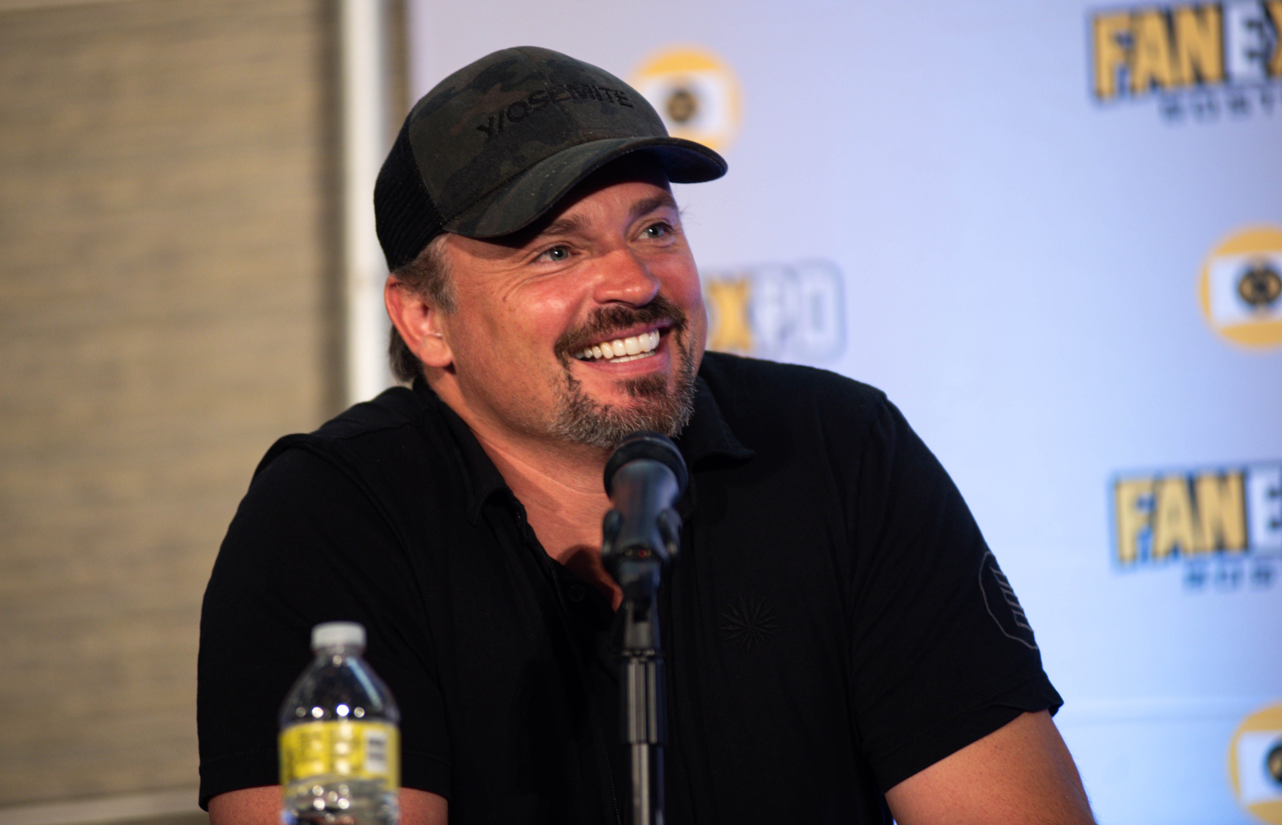 Matthew Lewis at the Smallville panel, smiling as he sits in front of his microphone.