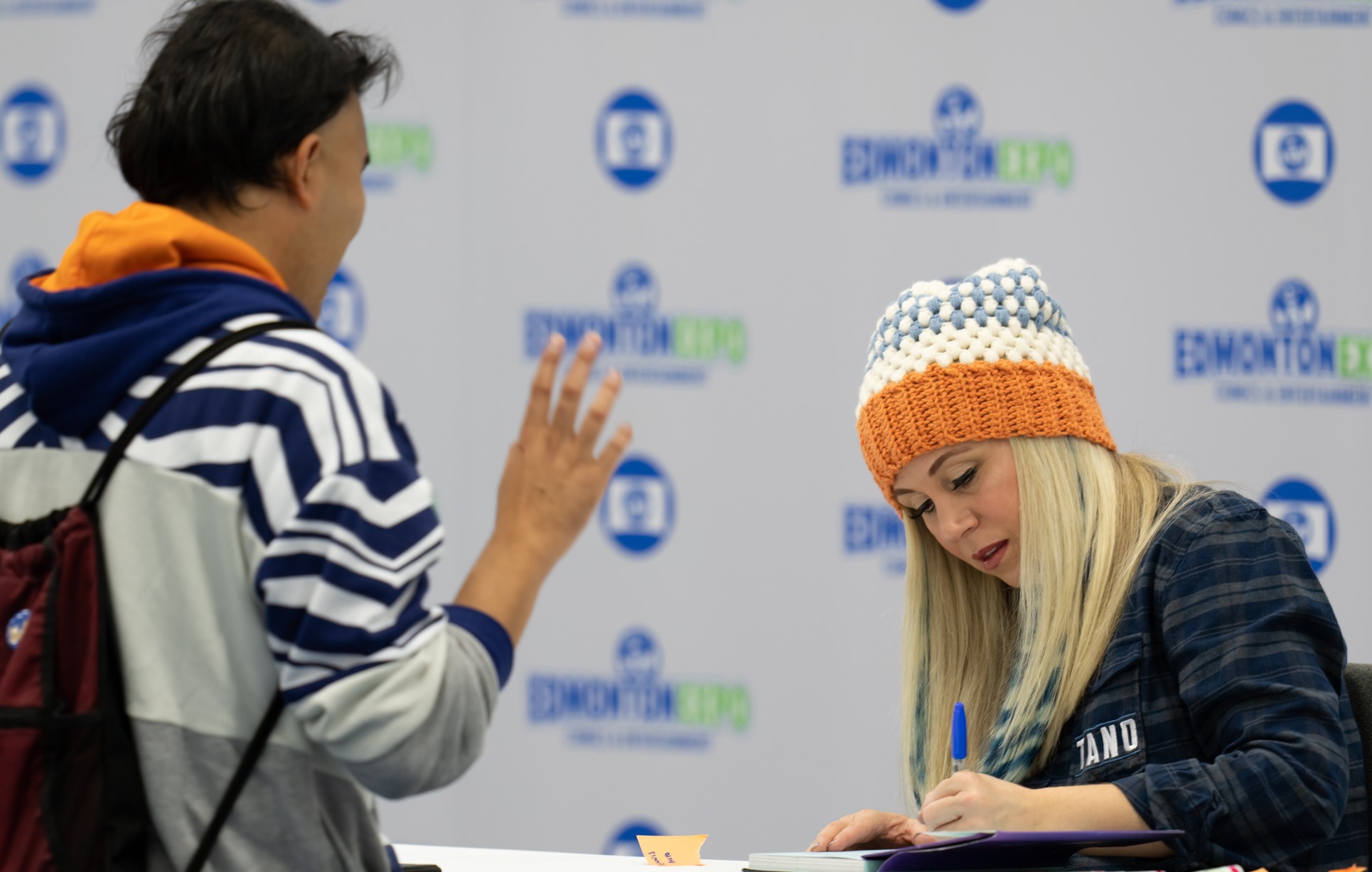 Ashley Eckstein signing something for a guest who is wearing an Ahsoka hoodie
