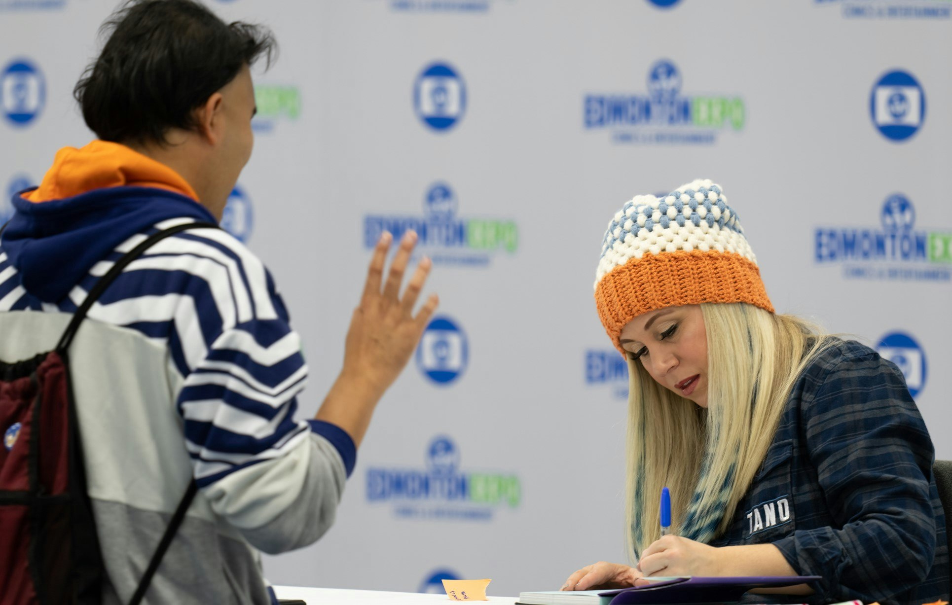 Ashley Eckstein signing something for a guest who is wearing an Ahsoka hoodie