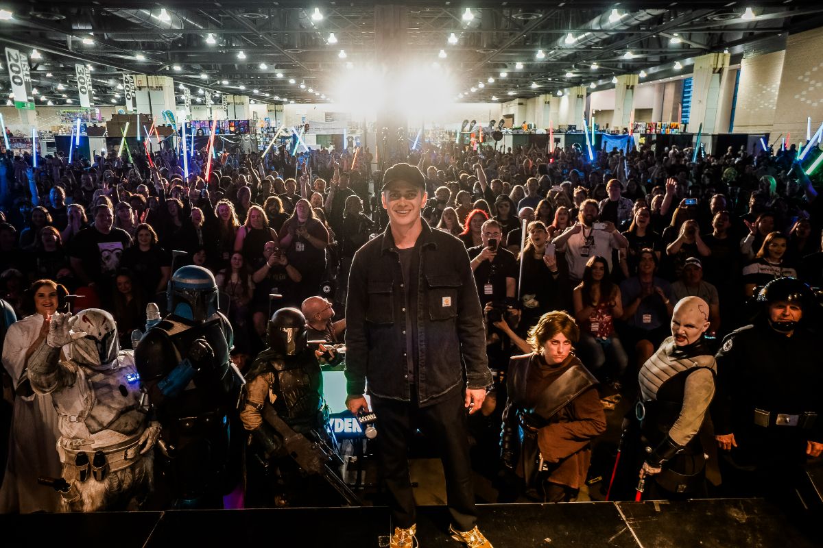 Hayden Christensen posing on stage in front of a crowd for a group picture