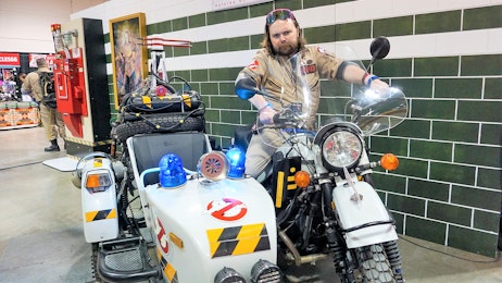 A ghostbusters cosplayer is sitting on a ghostbusters bike