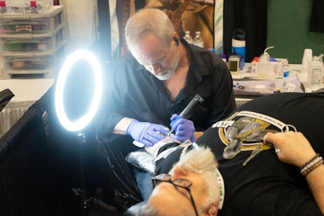 Tattoo artist working on an arm piece.