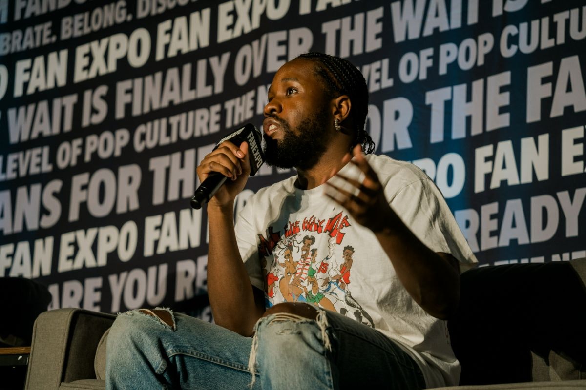 SHAMEIK MOORE SITTING ON A COUCH HOLDING A MICROPHONE AS HE TALKS