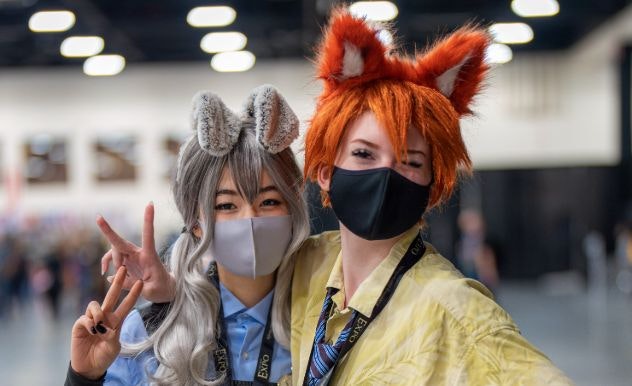 Two cosplayers, dressed as Nick & Judy from Zootopia, put peace signs in the air with their hands