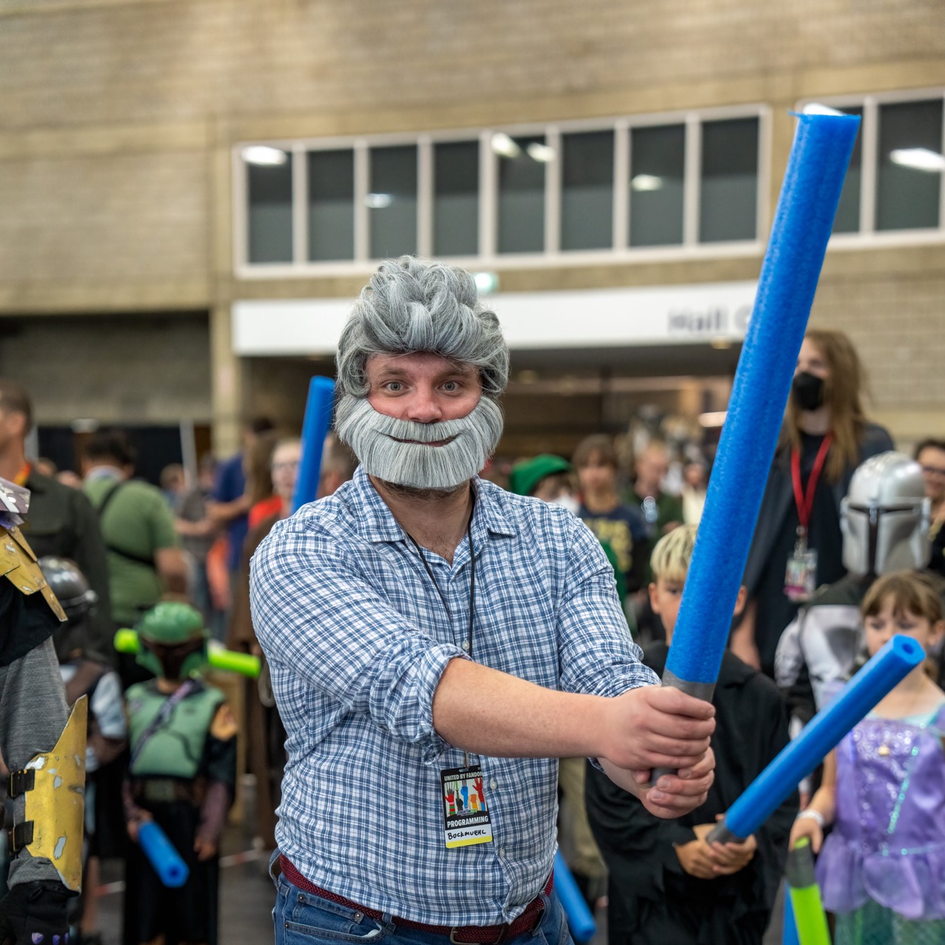 A George Lucas cosplayer holds a pool noodle lightsaber
