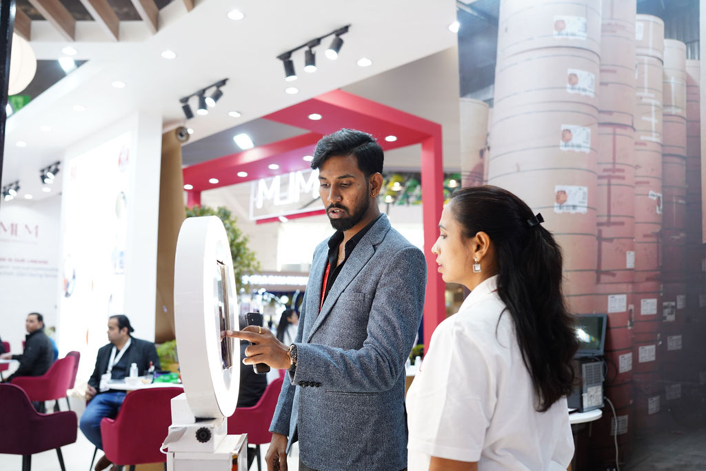 Group of professionals examining a red device at a trade show exhibition.