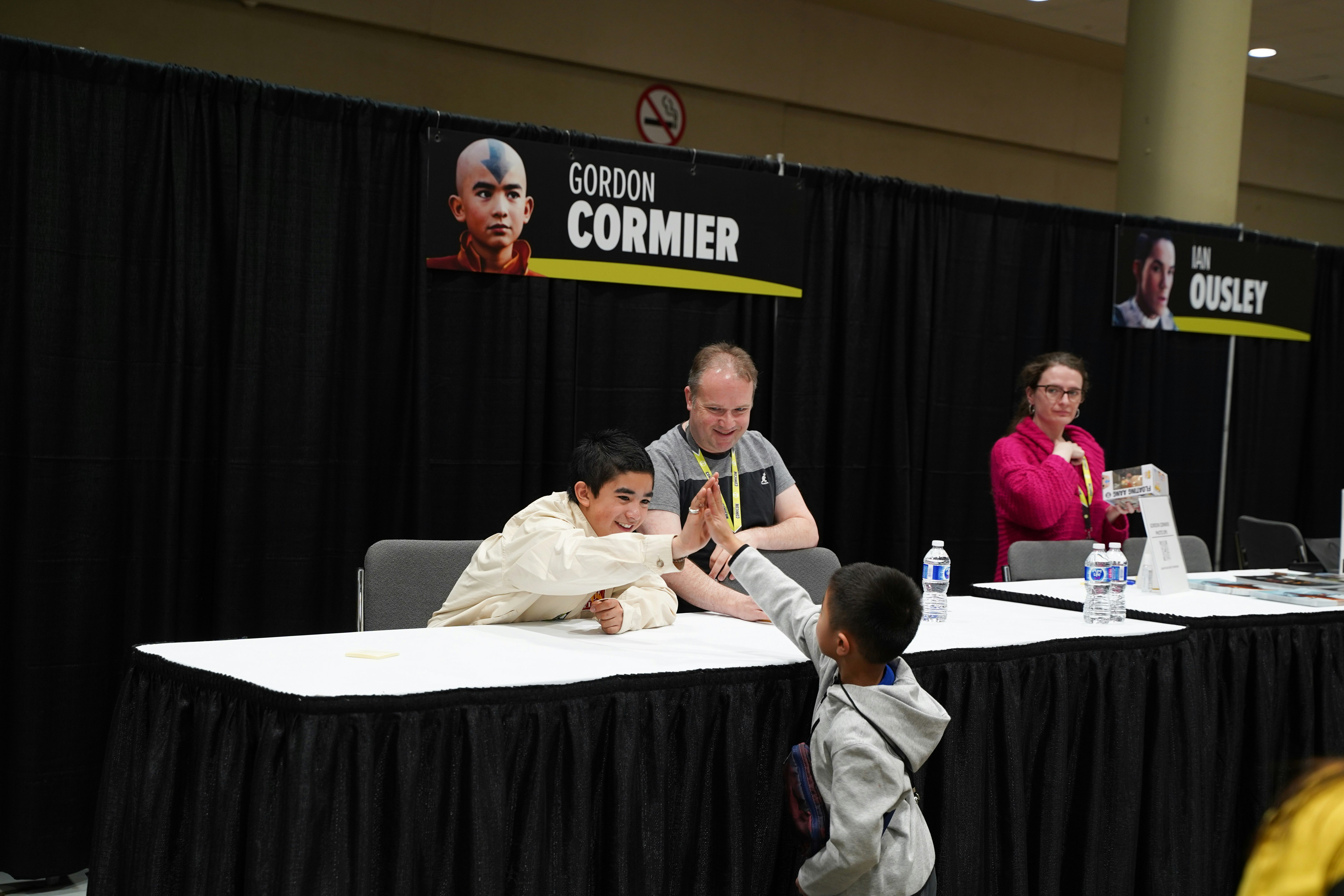 GORDON CORMIER, STAR OF AVATAR: THE LAST AIRBENDER, HIGH FIVES AND YOUNG CHILD WHO HAS APPROACHED THE TABLE TO MEET HIM