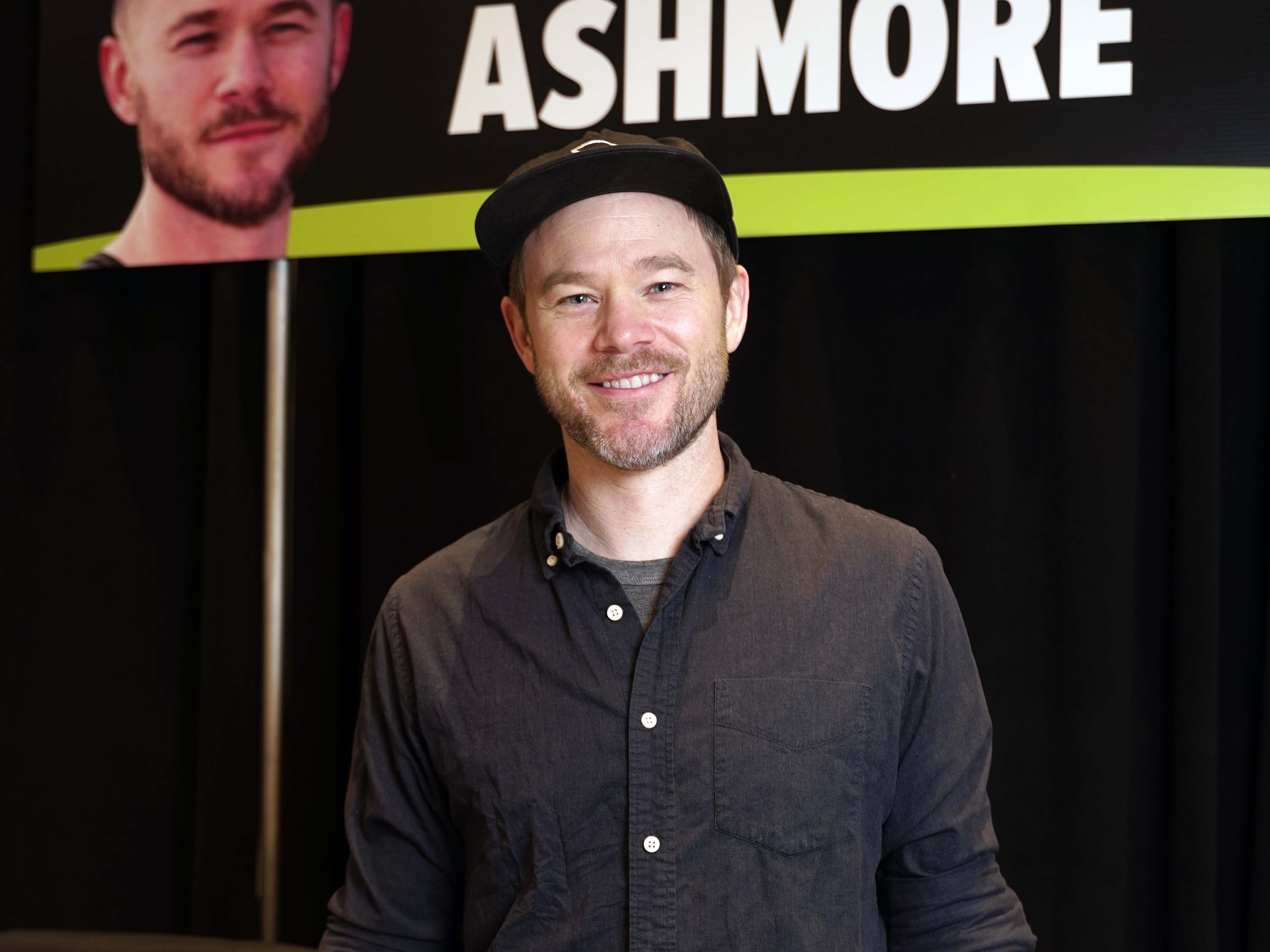 Aaron Ashmore posing infront of a sign with his face on it
