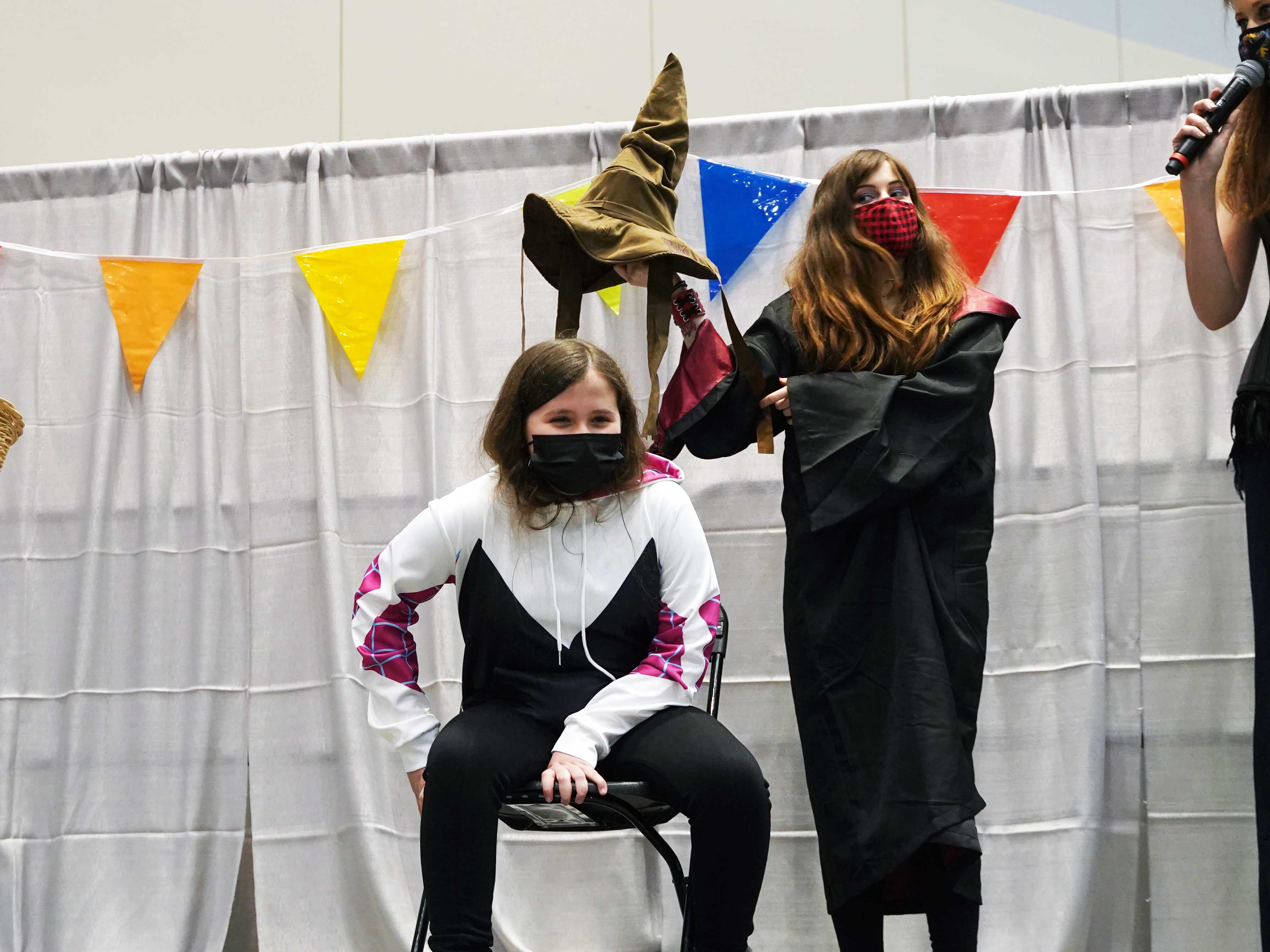 The Sorting Hat ceremony from Harry Potter happening with a fan in a Spider-Gwen cosplay
