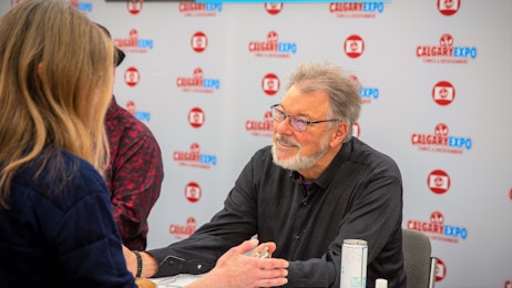 Jonathan Frakes is talking to a fan at his table