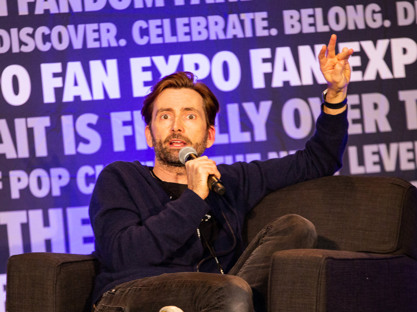 David Tennant on stage pointing a finger in the air