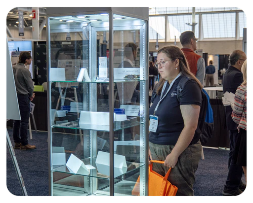 A woman stands in front of a display case, examining the items inside with a thoughtful expression.