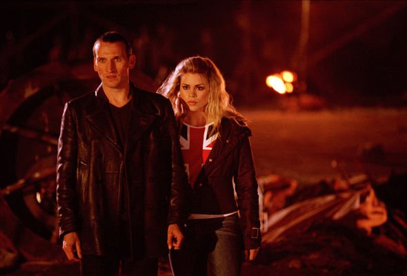 Fire rages in the distance; Rose and the Doctor stare on in concern amongst a pile of metal and other various forms of rubble and debris.