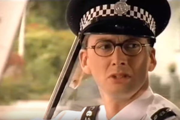 In a police style uniform, David Tennant looks confused/disgusted