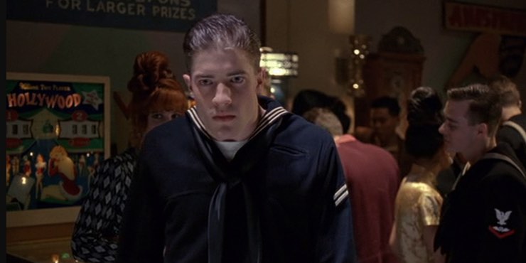 Brendan Fraser dressed as a sailor in a crowded bar and he is looking intensely at the camera